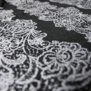 Detalle de la tela del fular tejido Yaro Jazz Duo Black, con un diseño de flores en blanco y negro.