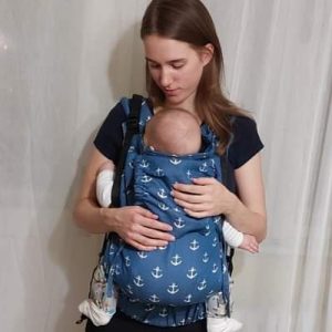 Madre porteando a su hijo con la mochila Yaro Hug Sailor Blue, de color azul marino con estampado de anclas blancas