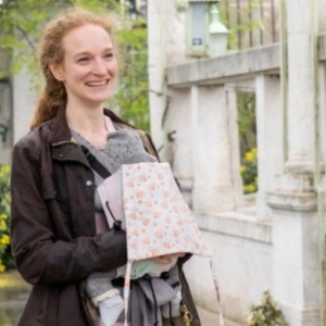 Madre sonriendo mientras portea a su bebé delante con la mochila Buzzidil Baby Evolution Cute Foxes, con un tierno estampado de zorritos naranjas.