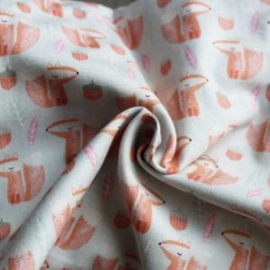 Primer plano del tejido de la mochila Buzzidil Cute Foxes, mostrando el patrón de zorros naranjas, bellotas y hojas sobre un fondo claro suave.