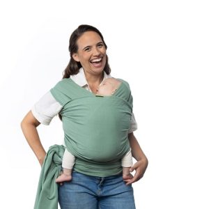 madre sonriendo sobre fondo blanco porteando tiernamente a su bebé recién nacido con un fular elástico en un bonito color verde salvia (Sage Green).