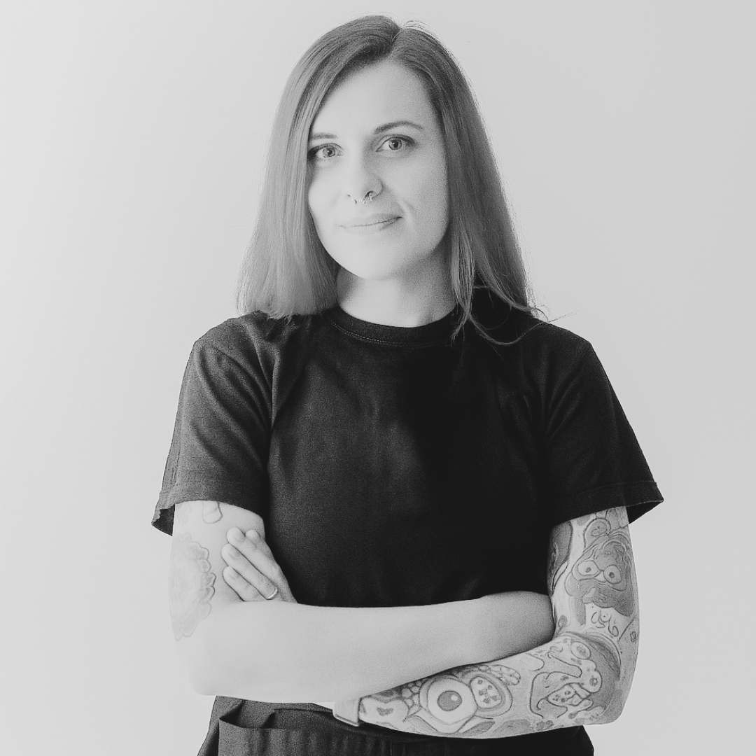 fotografía en blanco y negro de una mujer sonriendo con los brazos cruzados, alba que es docente en la escuela de porteo kangurearte con un collar de bolas sobre un fondo gris