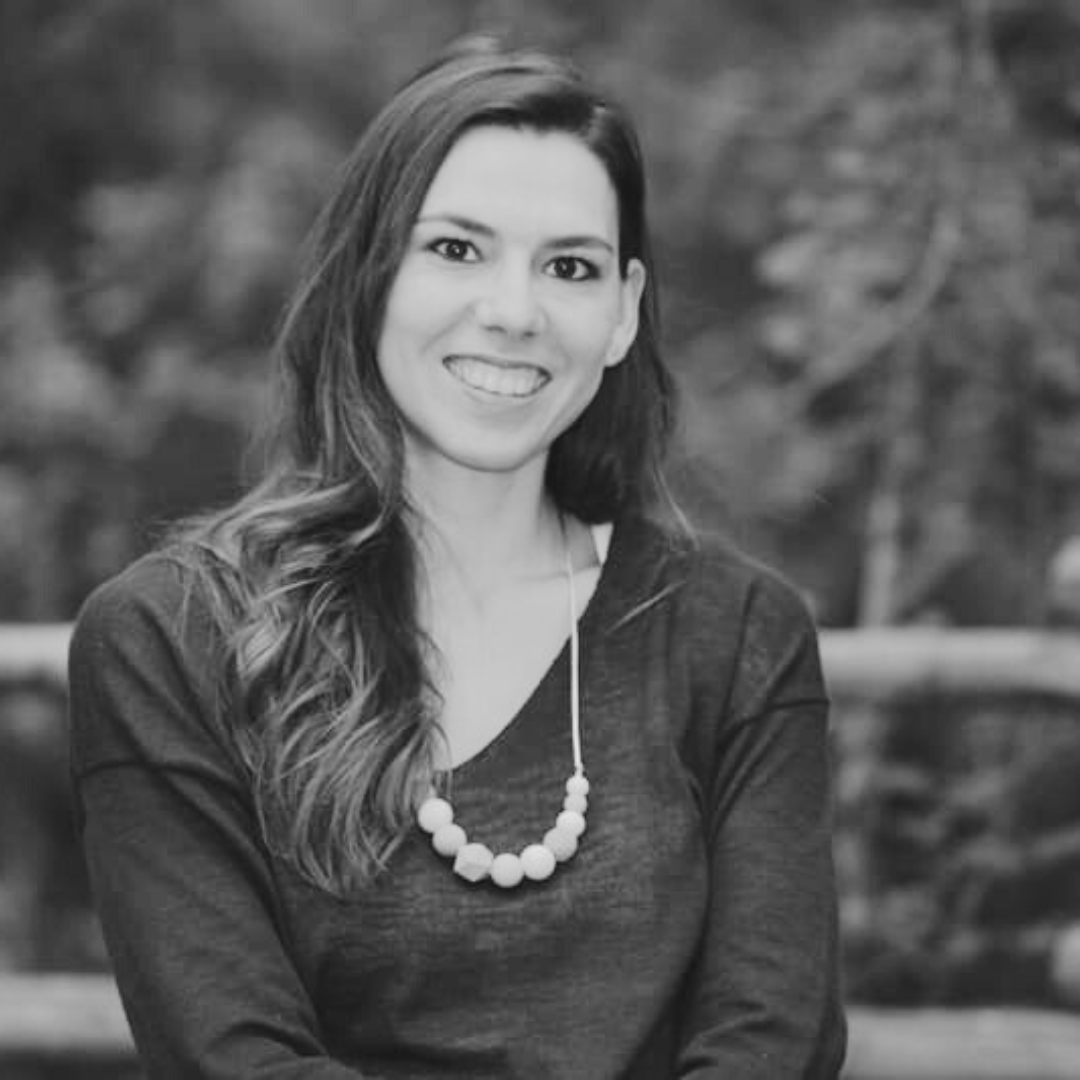 fotografía en blanco y negro de una mujer sonriendo, patricia que es docente en la escuela de porteo kangurearte con un collar de bolas sobre un fondo de parque con árboles