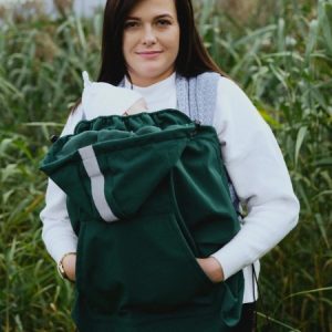 Mujer porteando a su bebé al aire libre, abrigado bajo un cobertor de porteo de tejido softshell de la marca Little Frog en color verde.