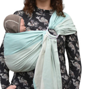 Madre porteando a su bebé en posición vertical con una bandolera de anillas Yaro color Mint (verde menta), mostrando las rayas suaves del tejido.