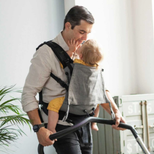Padre porteando cómodamente a su bebé al frente con la mochila Buzzidil Sherlock, mostrando un diseño elegante y unisex en tonos grises.