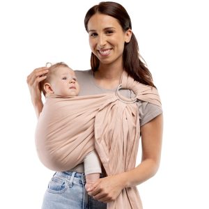 Fotografía de catálogo con fondo blanco de madre sonriendo con su bebé ergonómicamente alojado en la bandolera de anillas Boba Ring Sling color Peony Pink.