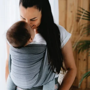 Plano medio de madre e hijo mirándose con ternura en postura ergonómica con el fular tejido de bambú Little Frog Angelite.