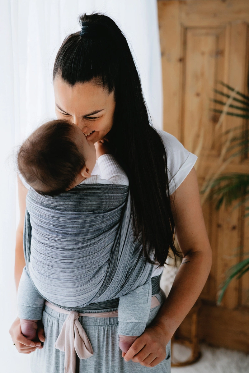 Plano medio de madre e hijo mirándose con ternura en postura ergonómica con el fular tejido de bambú Little Frog Angelite.