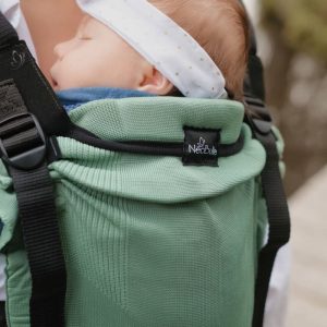 Plano detalle de un recién nacido dormido con cinta blanca en la cabeza reclinado sobre el panel transpirable verde menta de la mochila Néobulle My Néo.